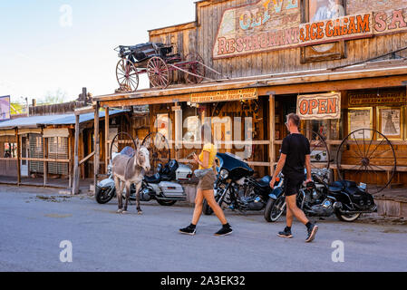 A couple of tourists walk by a wild burro in Oatman, Arizona. Stock Photo