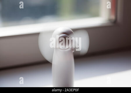 a small white table fan that stands in the windowsill when it is warm outside and indoors Stock Photo