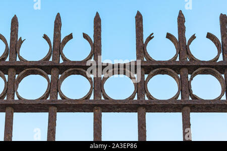 closeup detail of an antique rusting wrought iron fence at the old train station in Tel Aviv Israel with a clear blue sky background Stock Photo