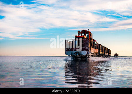 Old train rides on the railway laid in the water through the salt lake. train travels from water. Mined salt in Lake Burlin. Altai. Russia. Bursolith. Stock Photo