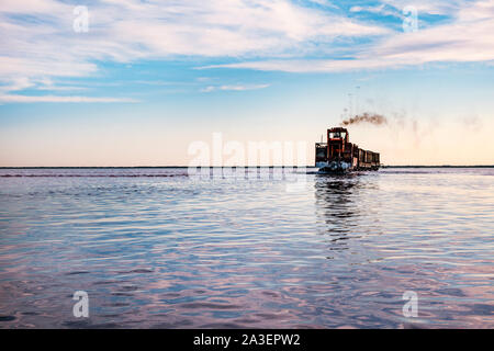 The train floats on the water against the blue sky. Salt industry, salt mining. Stock Photo