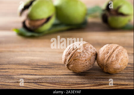 Two fresh ripe walnuts on the wooden background. Harvest Of Walnuts In A Green Shell. Autumn concept.Selective focus.Horizontal. Stock Photo