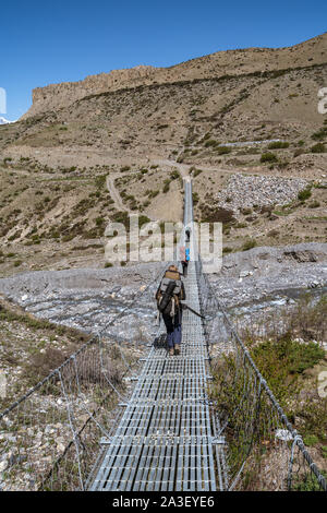 Trekkers crossing hong Khola river near Chongur village, Annapurna Circuit, Mustang district, Nepal Stock Photo