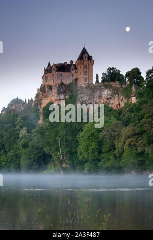 Cahteau Monfort Dordogne France at sunrise with the moon and mist on the Dordogne river Stock Photo