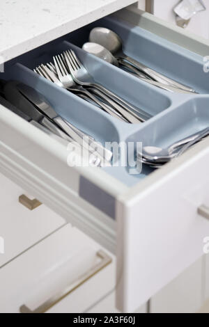 Open kitchen table drawer where stacked compartments forks spoons accessories, close up view no people Stock Photo