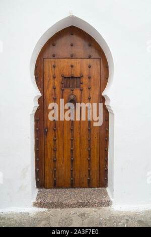 Old wooden door with brass decoration in the medina of Asilah, Morocco Stock Photo