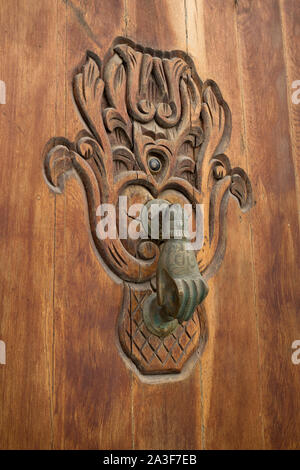 Old knocker in the shape of a hand on a wooden door in Asilah, Morocco Stock Photo