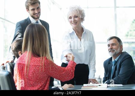 Smiling attractive mature businesswoman handshaking woman at meeting negotiation, happy hr senior executive woman shaking hand welcoming new hire part