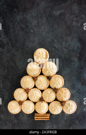 Mince pie Christmas tree with star anise and cinnamon sticks on black marble background. Top view. Stock Photo