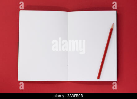Open blank notepad and red pencil on a red background, with copy space Stock Photo
