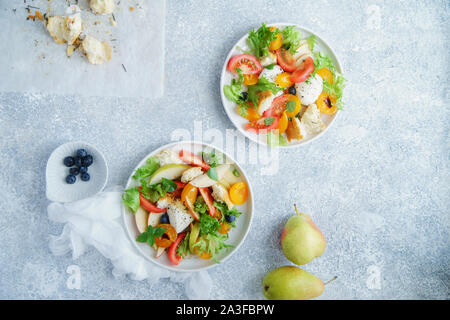 Original panzanella salad with mozarella, toasted baguette, tomatoes and plums on rustic background. Summer cuisine concept Stock Photo