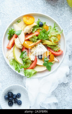 Original panzanella salad with mozarella, toasted baguette, tomatoes and plums on rustic background. Summer cuisine concept. Top view Stock Photo
