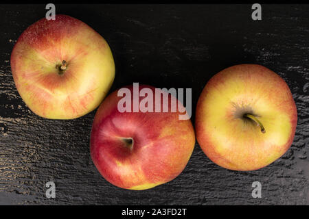 Group of three whole red apple jonagold flatlay on grey stone Stock Photo