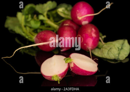 Group of five whole two halves of fresh red radish isolated on black glass Stock Photo