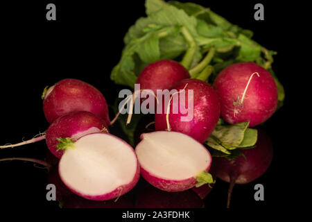 Group of five whole two halves of fresh red radish isolated on black glass Stock Photo