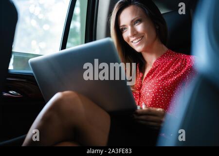 Businesswoman inside her car using a laptop Stock Photo