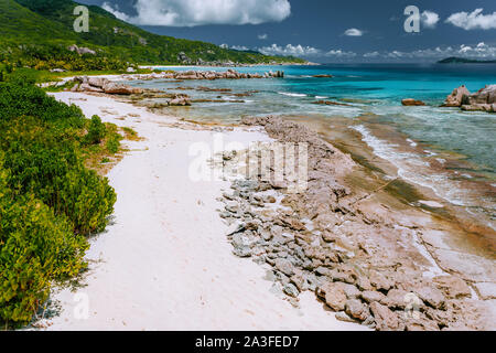 Old coral reef in the white sand beach on secluded beach of grand anse, La Digue, Seychelles. Aerial view. Stock Photo
