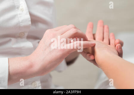 Professional female masseur giving reflexology massage to woman palm Stock Photo