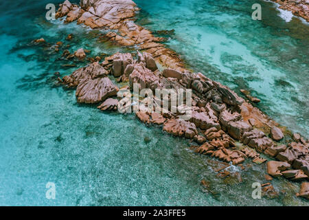 Aerial top view of granite rock formation surrounded by blue ocean lagoon. La Digue, Seychelles. Stock Photo