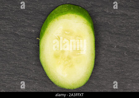 One piece of mini green cucumber flatlay on grey stone Stock Photo