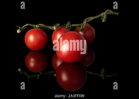 Group of four whole fresh red tomato isolated on black glass Stock Photo