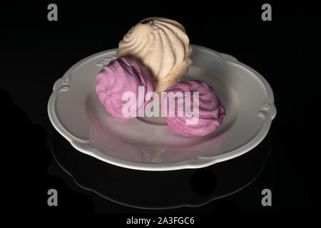 Group of three whole airy fresh pastel zefir on white plate isolated on black glass Stock Photo