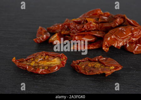 Lot of slices of dry red cherry tomato on grey stone Stock Photo