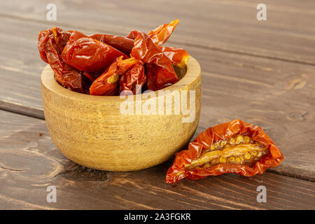 Lot of slices of dry red cherry tomato in wooden bowl on brown wood Stock Photo