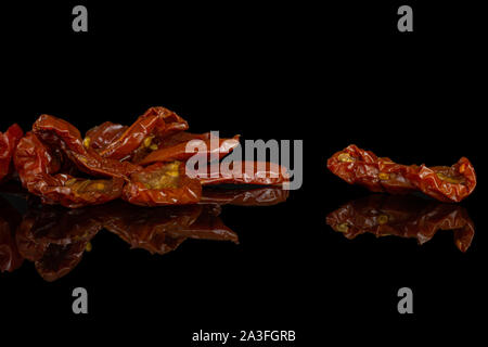 Lot of slices of dry red cherry tomato isolated on black glass Stock Photo