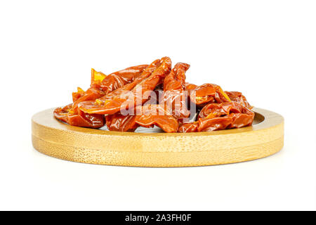 Lot of slices of dry red cherry tomato on bamboo plate isolated on white background Stock Photo