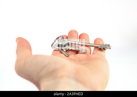A hand with a bunch of keys. A hand delivers a bunch of keys on a white background. Stock Photo