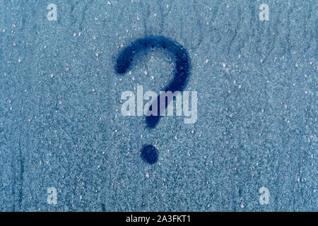 Frost patterns on window glass with question mark in winter, close up. Question mark on blue frozen window glass natural surface background Stock Photo