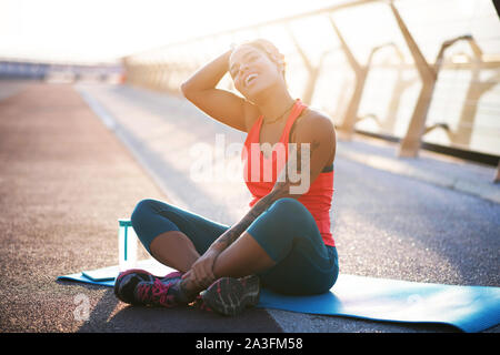 Woman with tattoo on arm loving sport practicing yoga outside Stock Photo