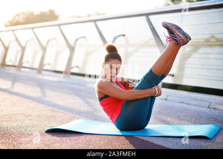 Dark-haired woman making funny face while doing yoga Stock Photo