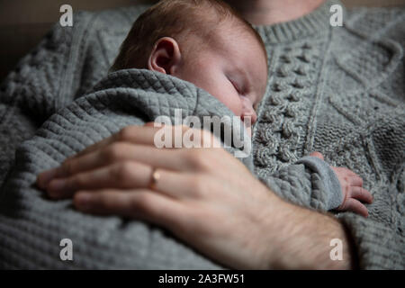 A father holding his baby son on his chest. Family bonding. Fatherhood Stock Photo