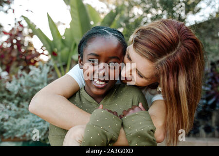 Joyful white mom hugs laughing black daughter Stock Photo - Alamy