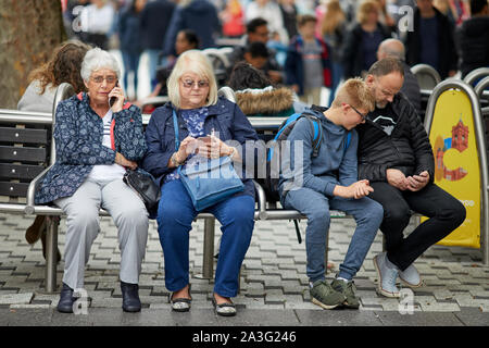 Cardiff Wales,   young and old using mobile phone technology  together Stock Photo