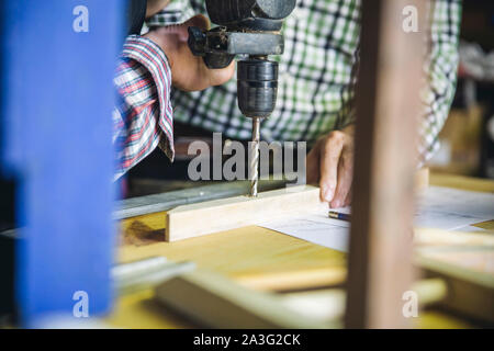 Unrecognizable couple drilling a wooden batten Stock Photo
