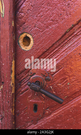 Closeup on old, wooden, red door with vintage door handle Stock Photo