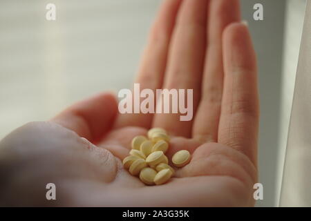 Heap of yellow medical pills in young female hand. Vitamins in human palm. Stock Photo