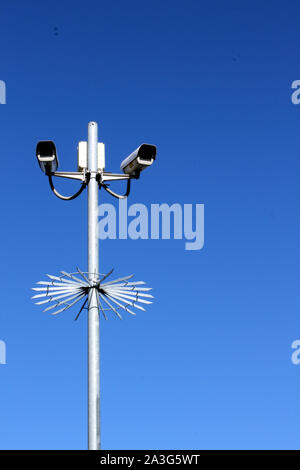 Upright view of security cameras on tall pole against deep blue sky Stock Photo