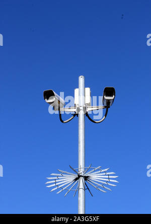 Upright view of security cameras on tall pole against deep blue sky Stock Photo