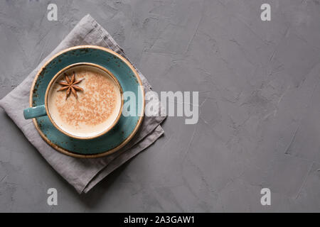 Masala Indian tea or coffee in blue cup with spices and cinnamon on black concrete table. Top view. Stock Photo