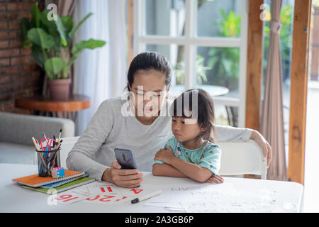 mother and daughter studying trough mobile phone device at home Stock Photo