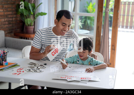 happy asian father teaching letter to her daughter at home. read and write lesson Stock Photo