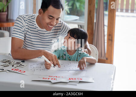 happy asian father teaching letter to her daughter at home. read and write lesson Stock Photo