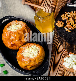 healthy food. Baked apples with cottage cheese and nuts lie in a black baking dish on a wooden table Stock Photo