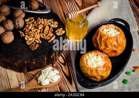 healthy food. Baked apples with cottage cheese and nuts lie in a black baking dish on a wooden table Stock Photo