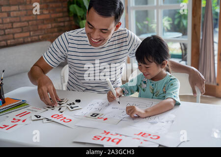 happy asian father teaching letter to her daughter at home. read and write lesson Stock Photo