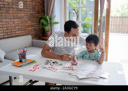 happy asian father teaching letter to her daughter at home. read and write lesson Stock Photo